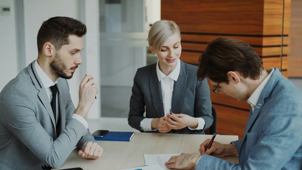 Abogados firmando un contrato con un cliente en una mesa de reuniones
